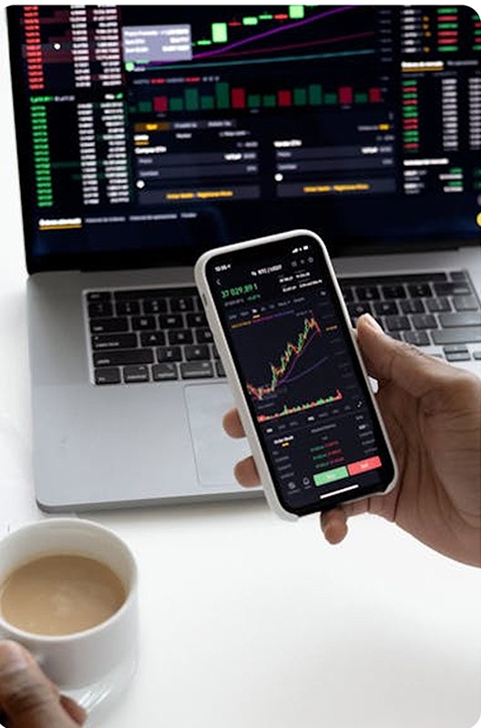 Trader analysing live charts on phone and laptop